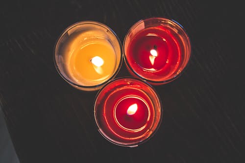 Lighted Red Wax Candle on Clear Drinking Glass