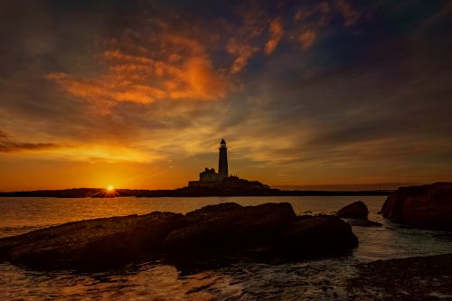 Free Breathtaking sunset view of St Mary's Lighthouse on the rocky coast. Stock Photo