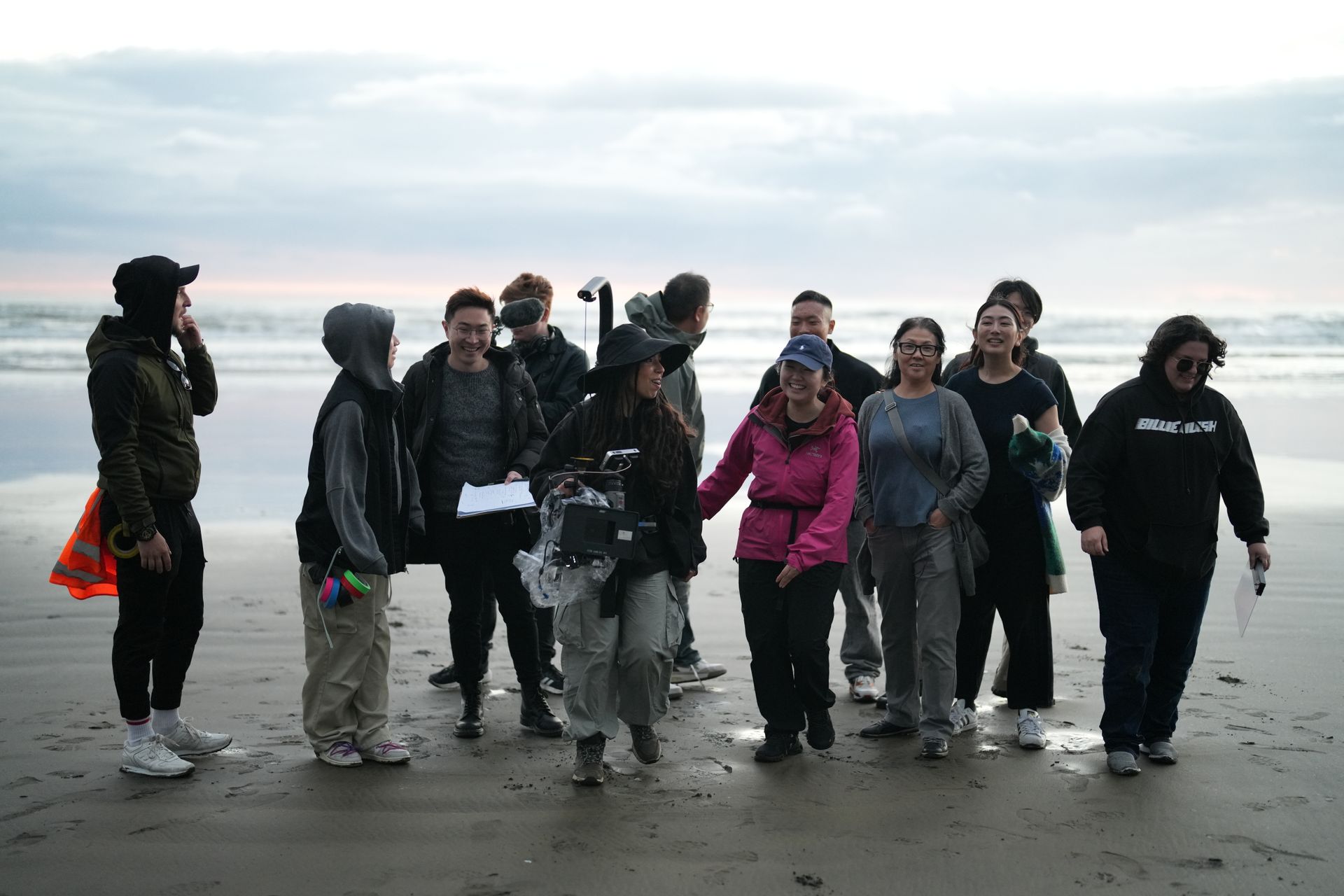 A diverse group of filmmakers capture scenes on a scenic seashore location.