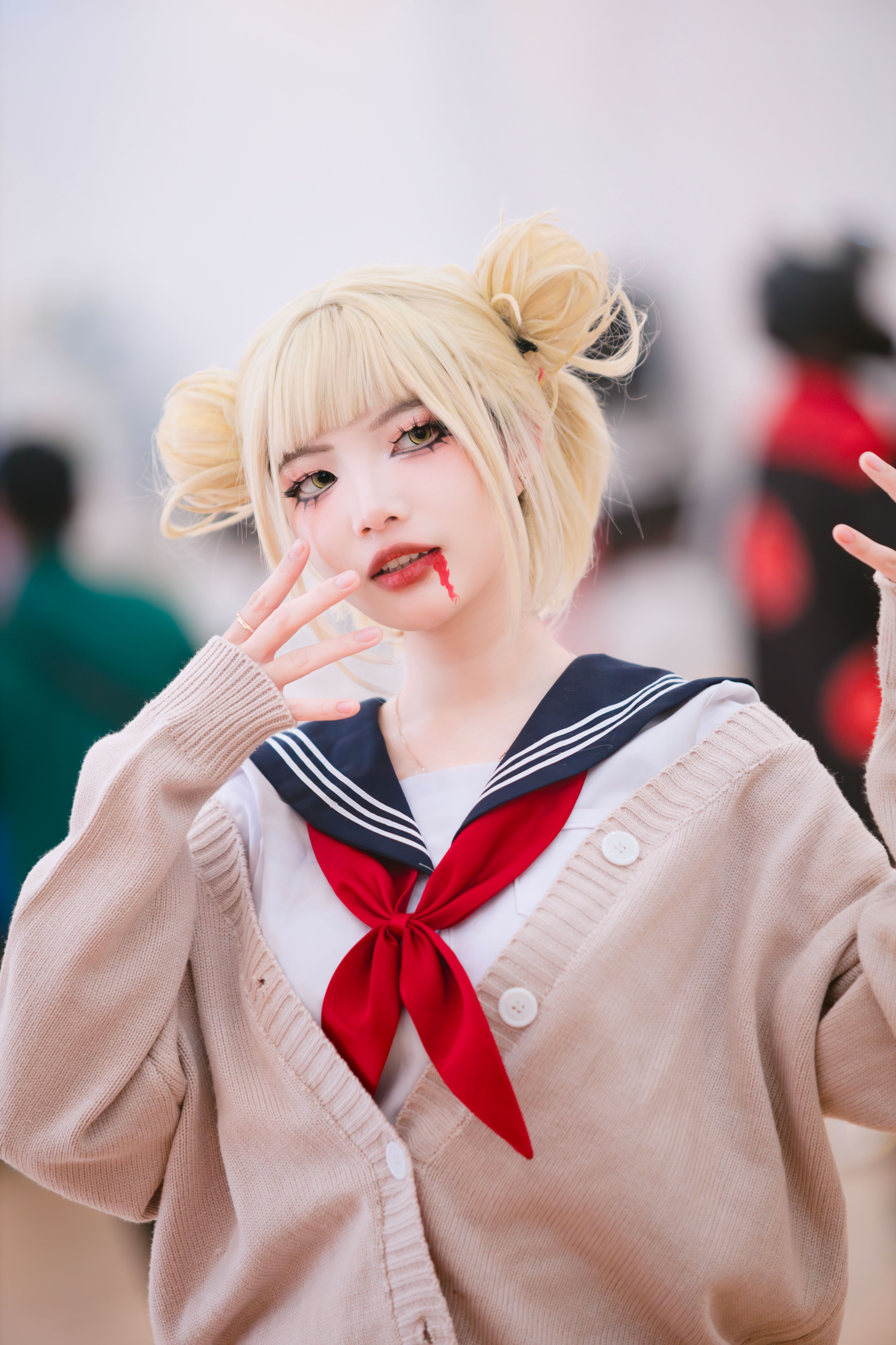 Young woman in anime cosplay with blonde hair and dramatic makeup at a convention.