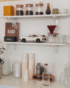 A cozy café shelf featuring coffee essentials, toy car, and decor jars.