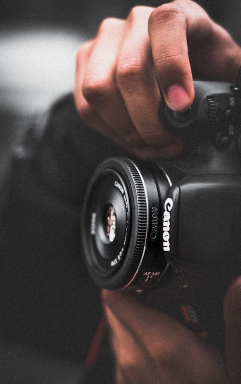 бесплатная человек держащий черный камеры Canon Dslr мелком фокус фотографии Стоковое фото