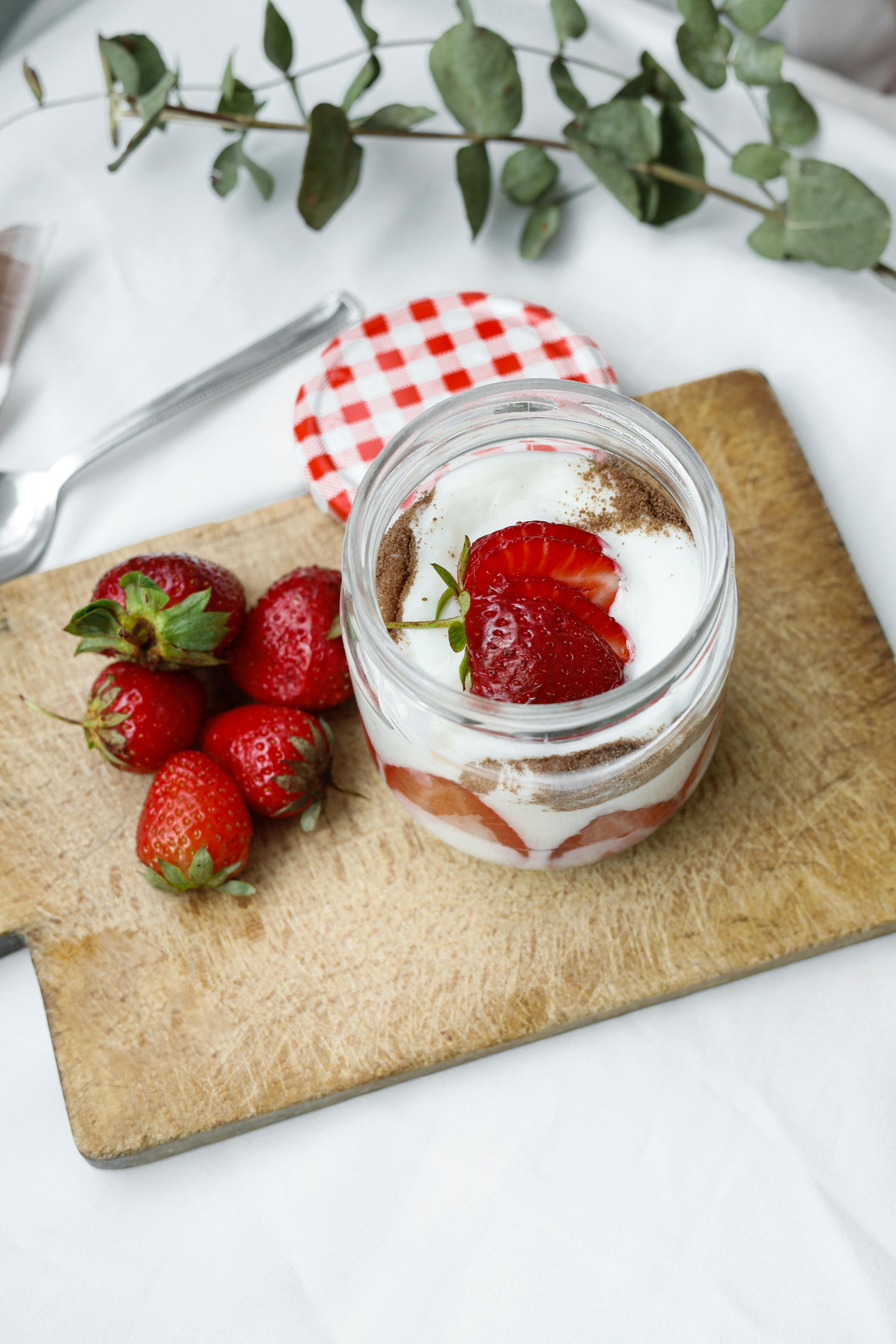Delicious layered yogurt with fresh strawberries on a wooden board, perfect for a healthy snack.