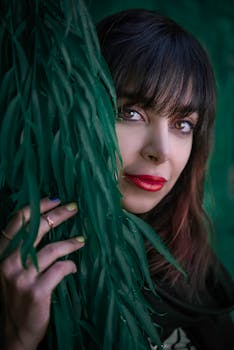 一张女人的特写肖像，红唇被郁郁葱葱的绿叶环绕