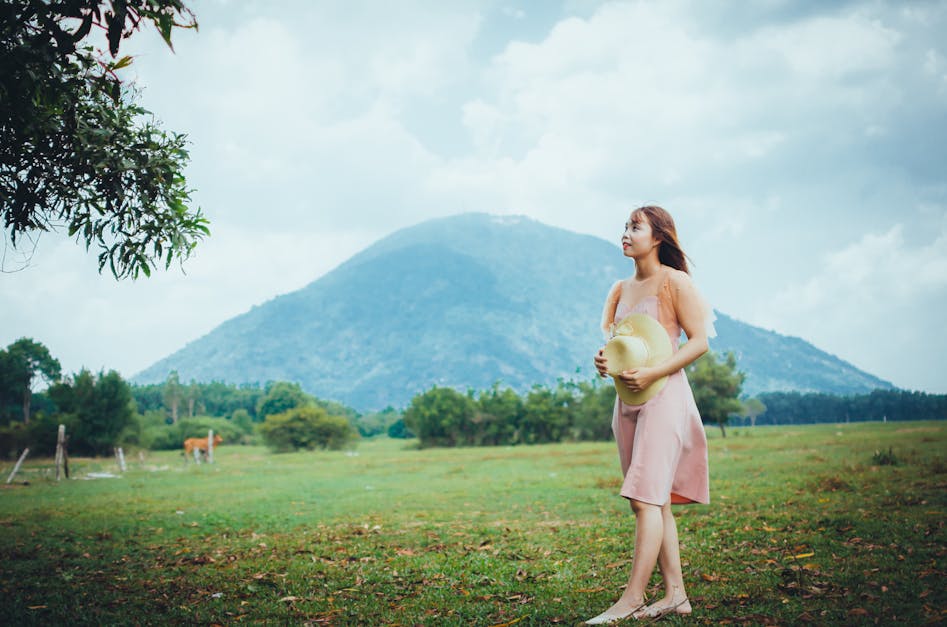 Photo Of Woman Standing Near Tree Holding A Sun Hat While Looking Up