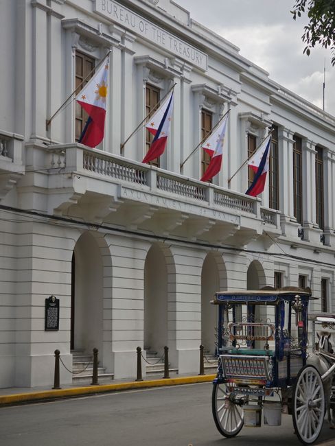 Horse cart in front of the Bureau of the Treasury in Manila, adorned with Philippine flags.