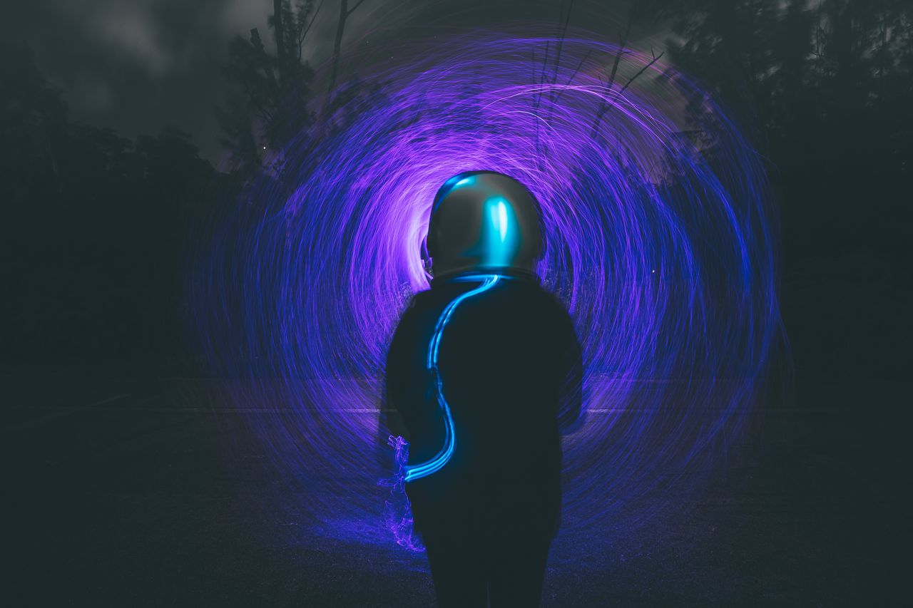 astronaut silhouette with vibrant blue and purple light trails in a ni