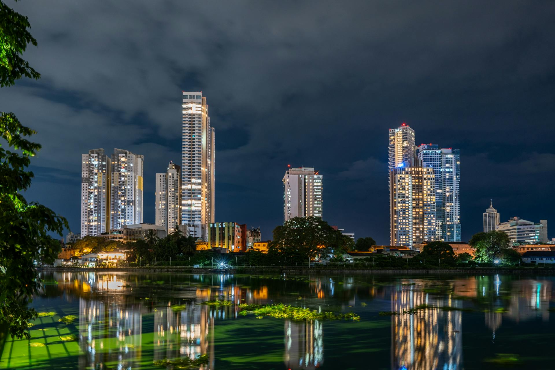 Stunning night view of Colombo skyscrapers reflecting over Beira Lake.