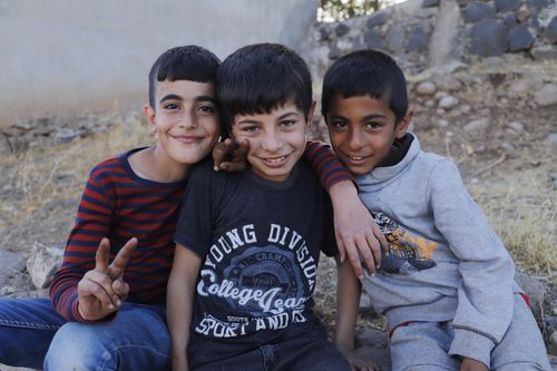 Free Three cheerful boys sitting and posing outdoors in Diyarbakır, Türkiye. Stock Photo