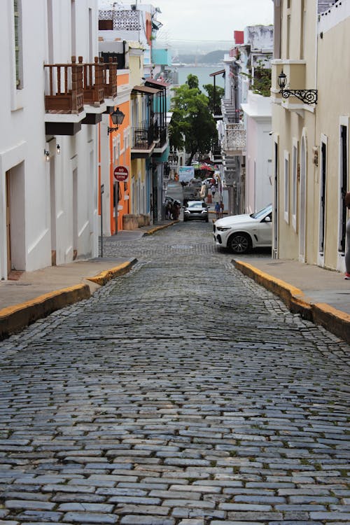 A cobblestone street with cars parked on it