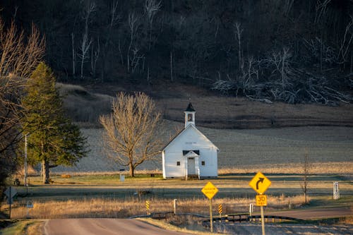 A small white church sits on a country road