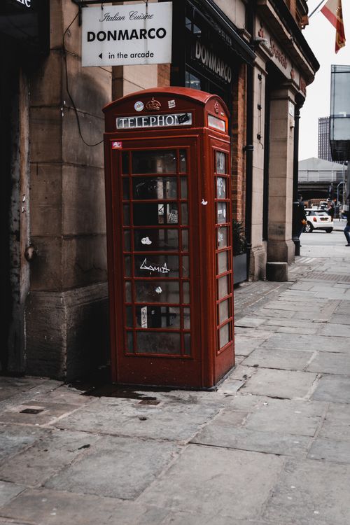 Free Iconic red telephone booth on a sidewalk in Manchester, UK, with vintage urban vibes. Stock Photo