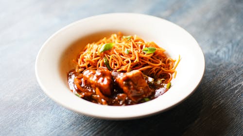 A bowl of noodles with meat and sauce on top