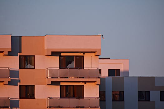 Modern apartment building with glass balconies in Iași, Romania, lit by sunset.