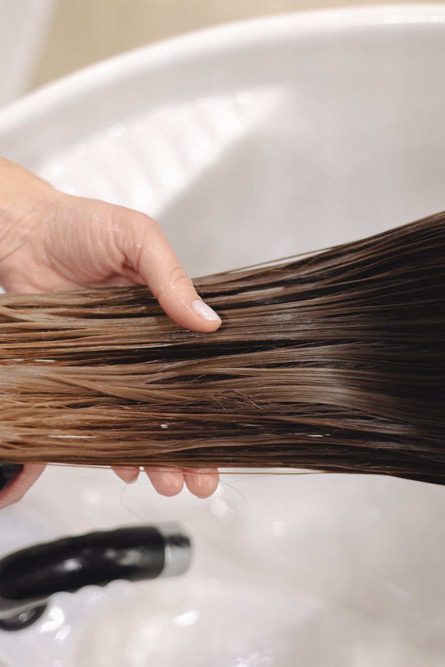 Wet hair held over a basin before a gentler shampoo wash