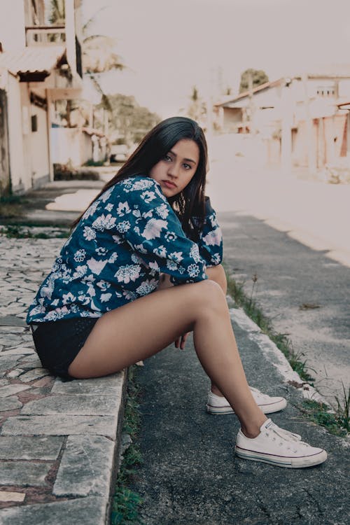 Free Woman Sitting on Concrete Pathway Near Road Stock Photo