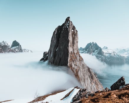 Epic winter landscape of sharp mountain peaks surrounded by mist in Troms, Norway.