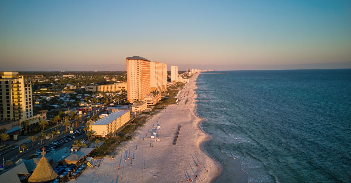 A stunning aerial view of a coastal city with tall buildings and a beautiful beach at sunset.
