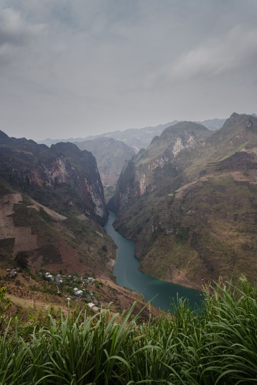Free Aerial view of a winding river in a lush canyon surrounded by rugged mountains. Stock Photo