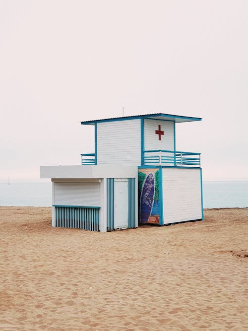 A lifeguard stand on the beach with a red cross on it