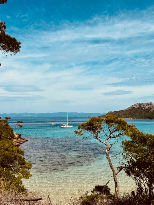 Free Beautiful seaside vista with calm waters and anchored sailboats under a clear sky. Stock Photo
