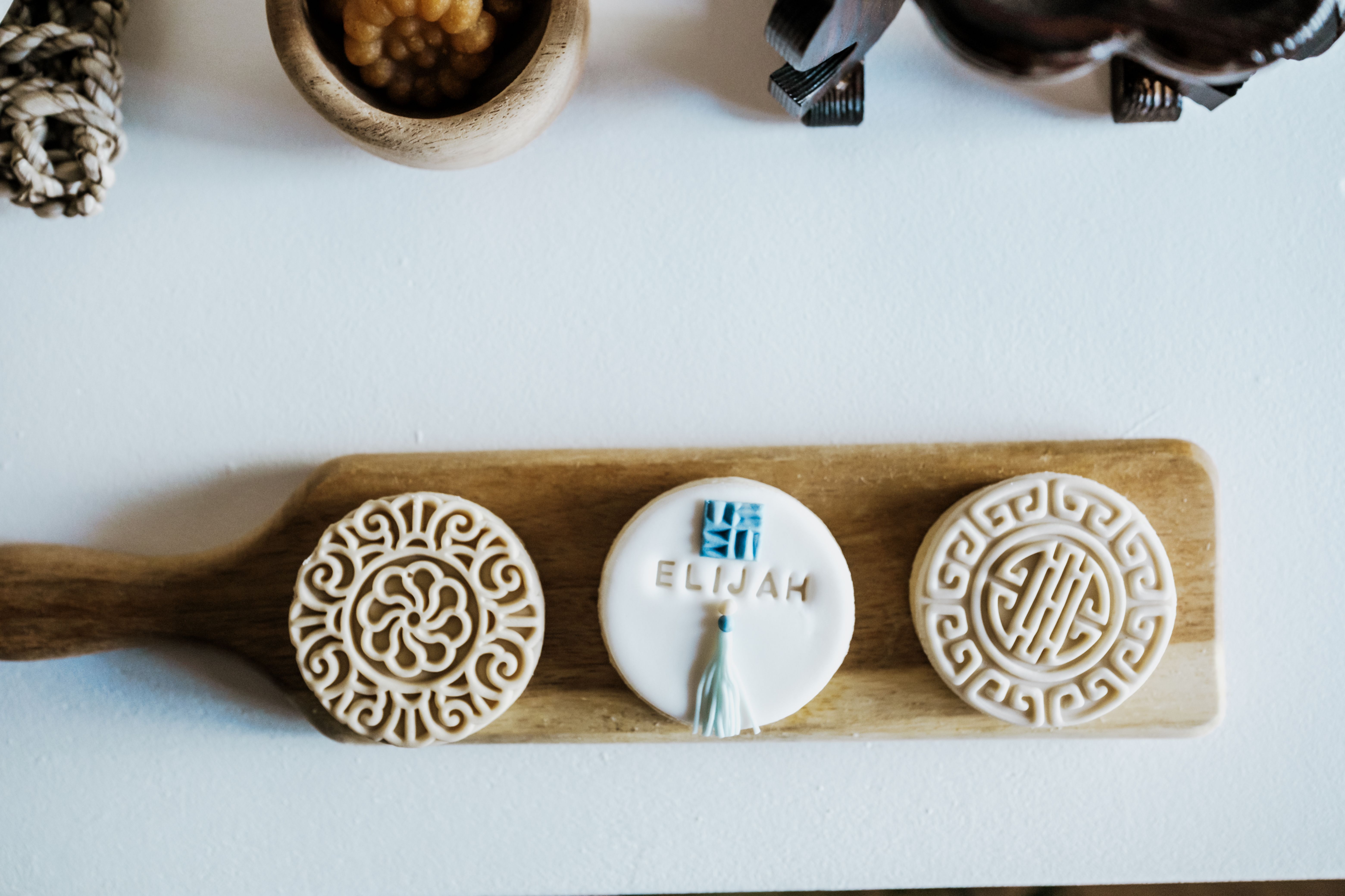 Top view of intricately designed handmade cookies on a wooden tray, featuring custom text 'Elijah'.