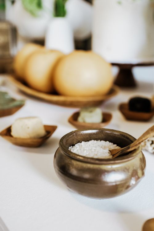 Free Elegant still life featuring rice in a rustic pot with surrounding decorative elements on a white background. Stock Photo