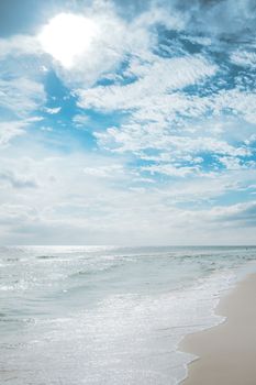 Tranquil beach with gentle waves under a bright sky, perfect for relaxation themes.