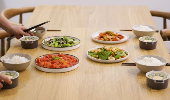 A delightful spread of Asian dishes including rice and vegetables on a wooden table, perfect for dining.