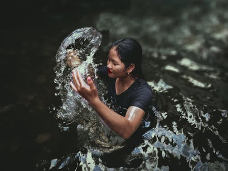 Woman playing with water outdoors in Kalimantan, Indonesia. Refreshing and joyful scene.