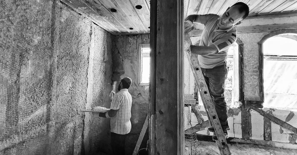 Zwei Handwerker verputzen einen Innenraum
