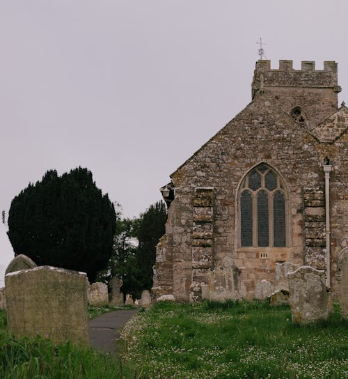 A stone church with a graveyard in the background