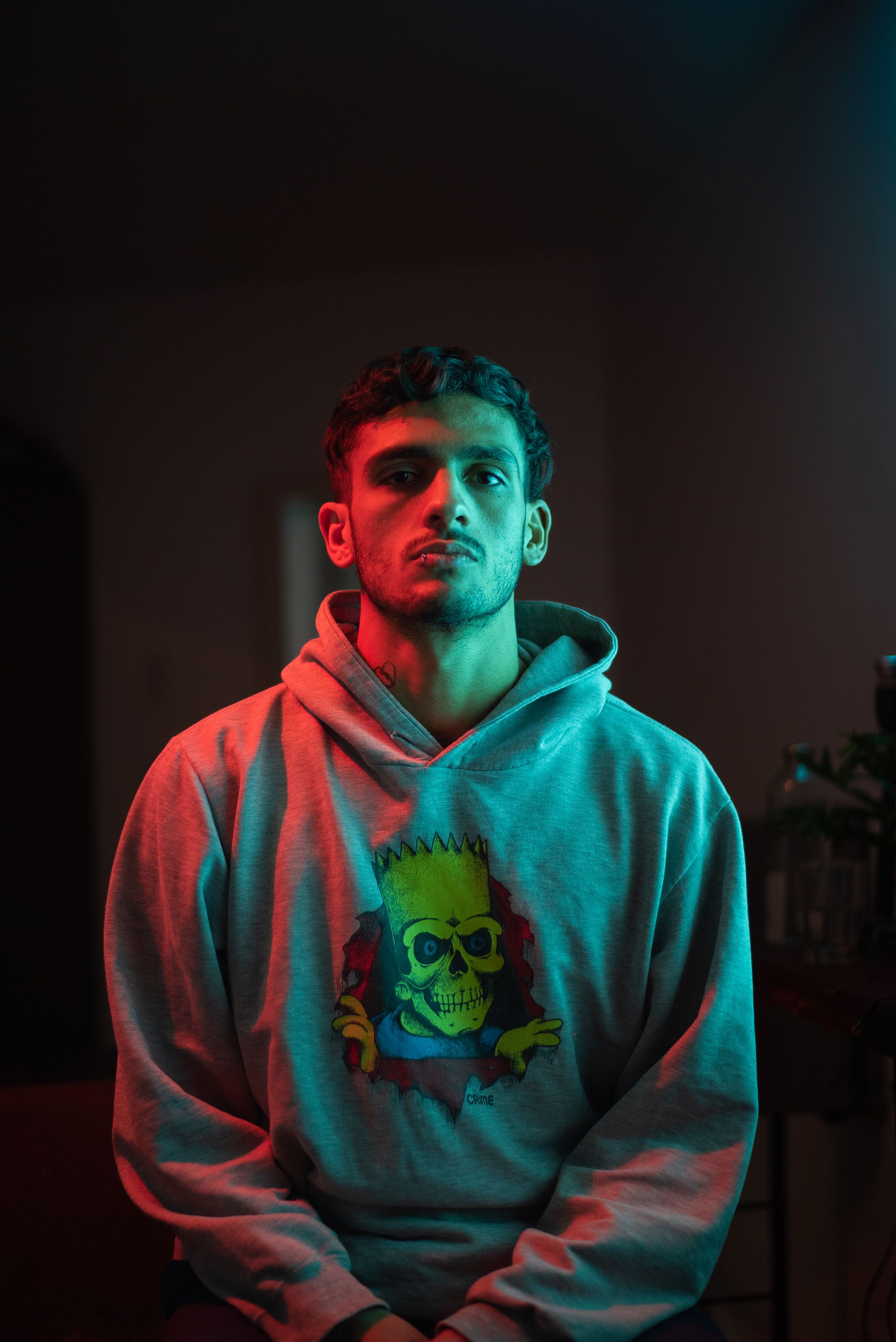 A young man poses in a vibrant hoodie with creative lighting effects.