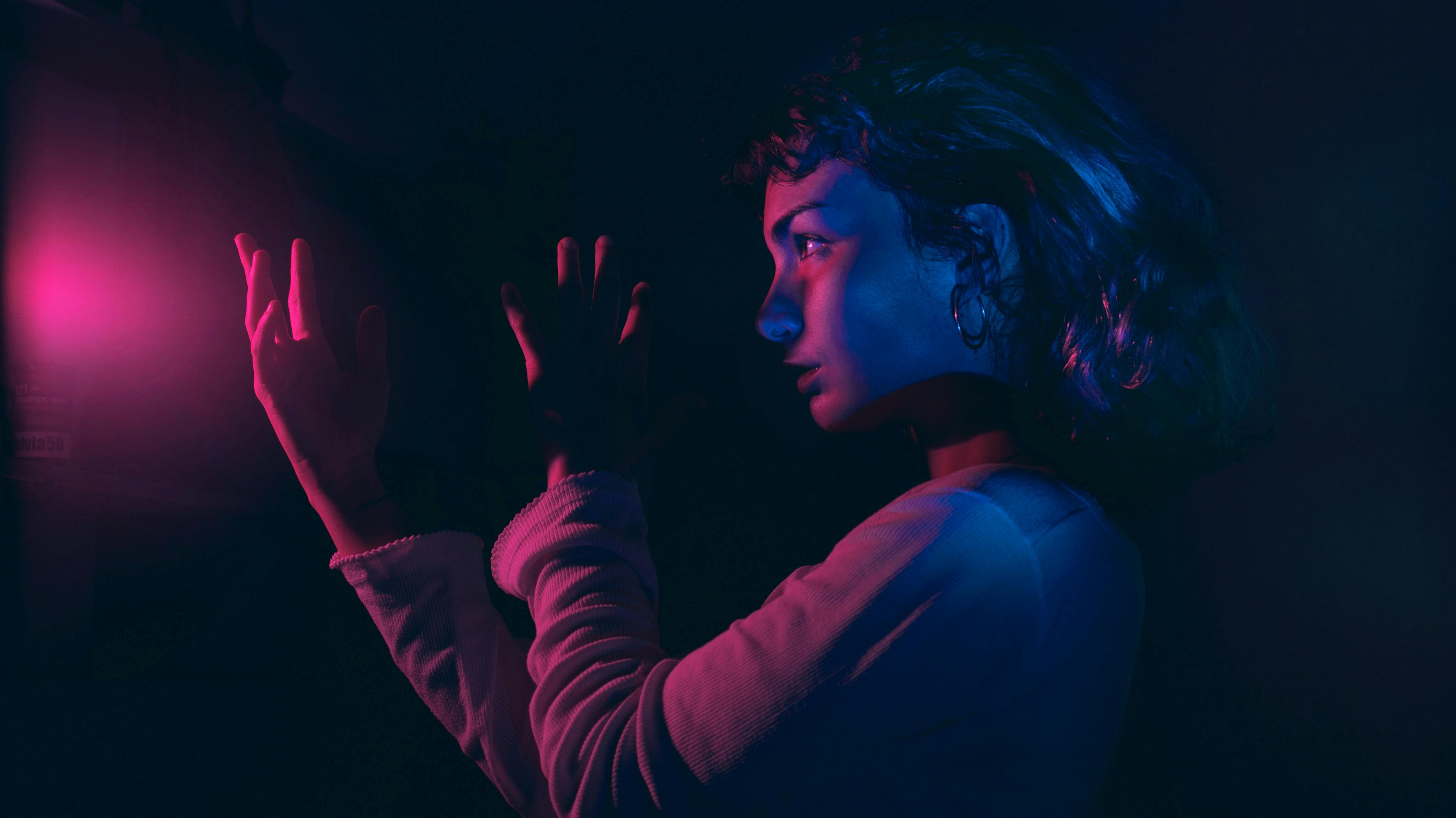 Artistic portrait of a woman in neon pink and purple lighting, creating a moody atmosphere.