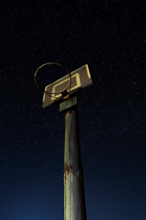 A basketball hoop on a pole at night