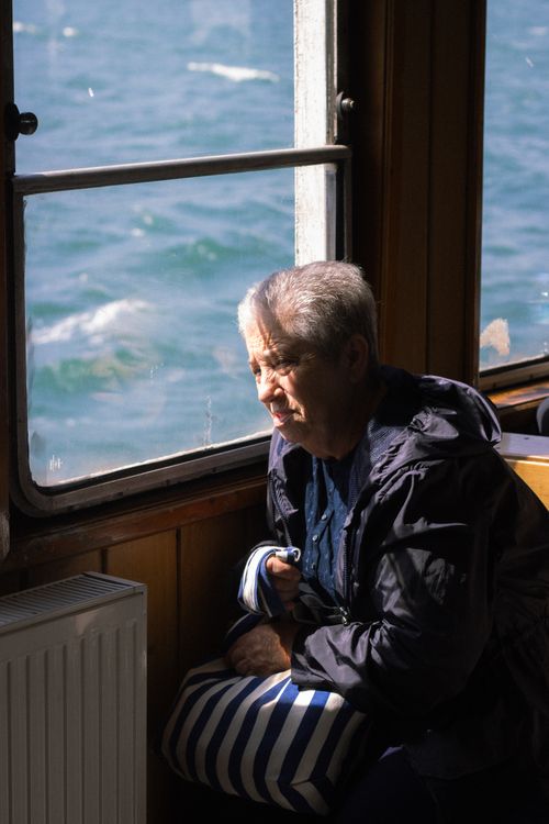 Free Elderly woman reflecting by the sea on a ferry during a sunny day. Stock Photo