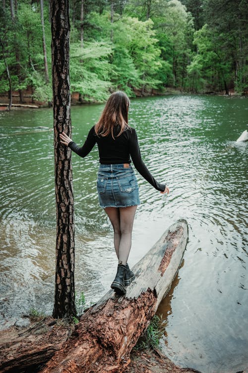 A woman standing on a log in the middle of a river