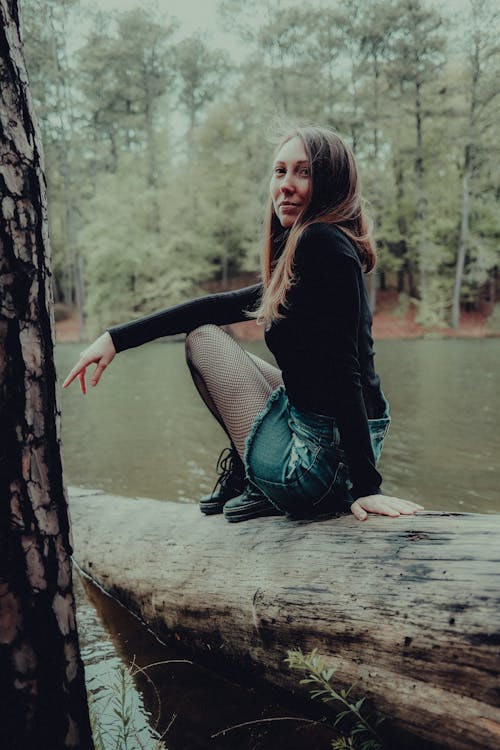 A girl sitting on a log in the woods