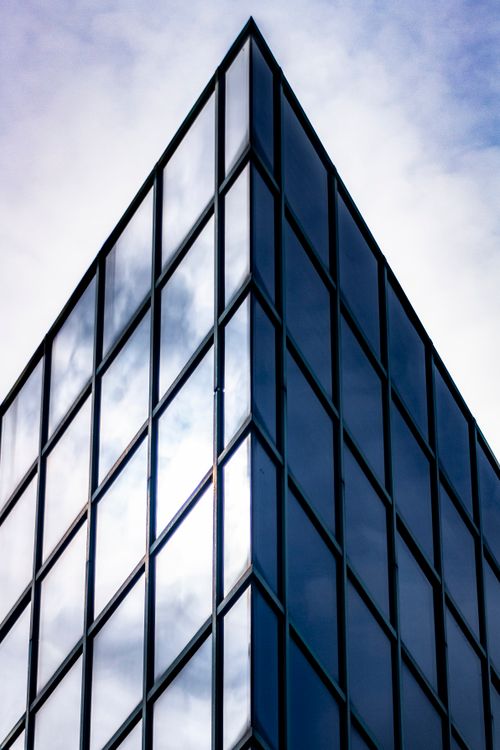 Free Close-up of a glass skyscraper facade in Brescia, reflecting the sky's light. Stock Photo