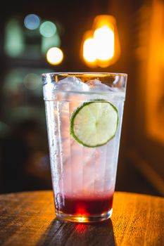 Cool cocktail with a lime slice, ice, and vibrant lighting in a bar setting.