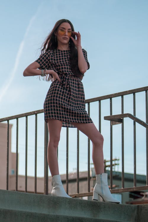 Free Woman in Brown and Black Checked Mini Dress Standing on Top of Stairs Stock Photo