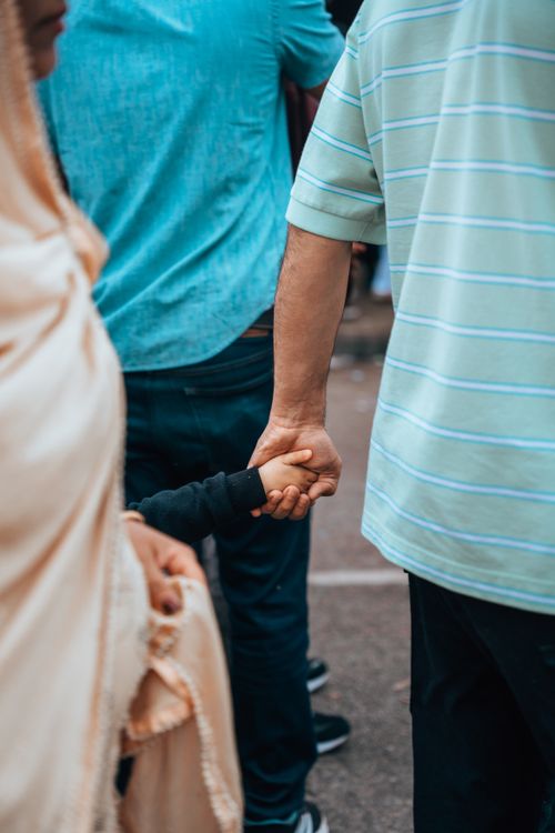 Free A candid shot of a parent and child holding hands while walking on a city street. Stock Photo