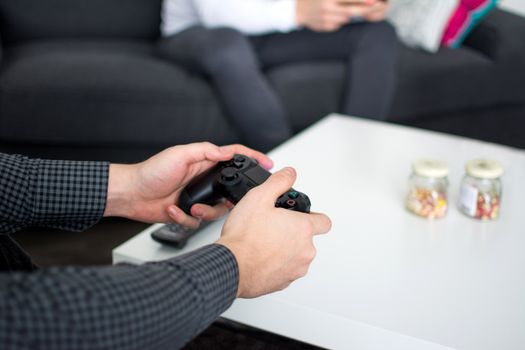 Close-up of hands holding a gaming controller, depicting leisure activity in a living room setting.