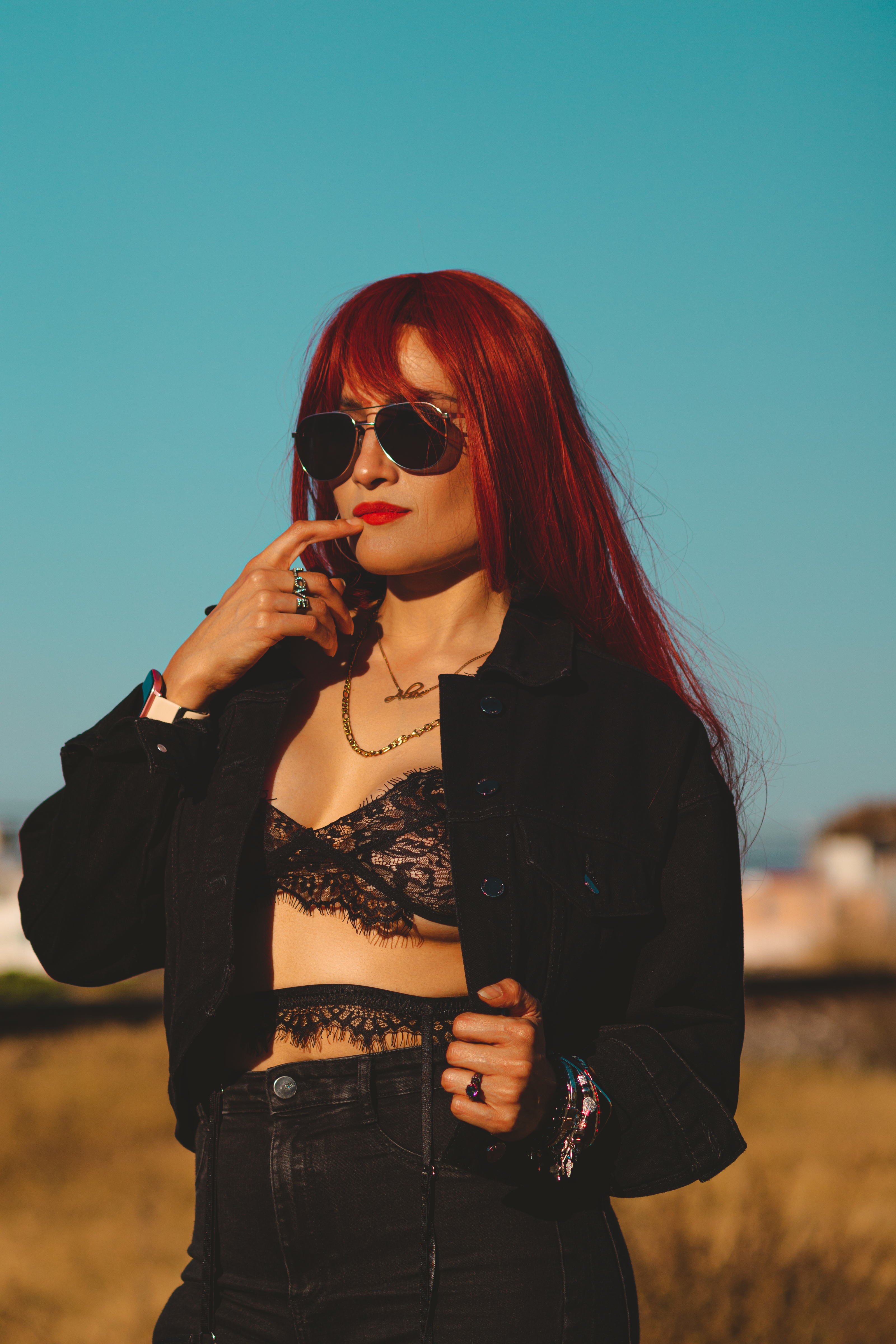 Jovem mulher elegante com cabelo vermelho e óculos de sol em um look estiloso ao ar livre.