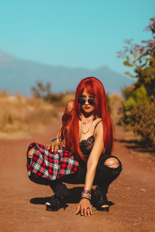 Free Stylish woman with red hair poses in desert, showcasing modern fashion. Stock Photo