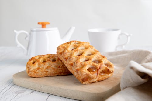 Two pieces of bread on a cutting board with a cup of tea