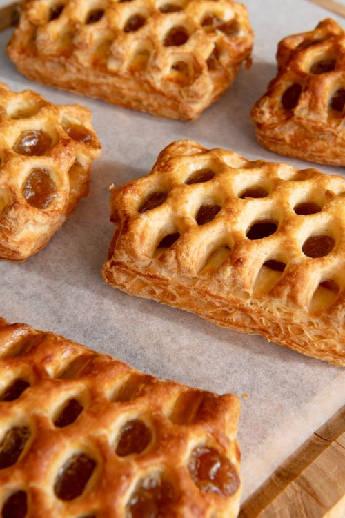 Free Freshly baked lattice pastries arranged on parchment paper, showcasing golden brown, flaky texture. Stock Photo