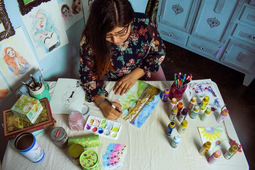 Female artist painting in a vibrant art studio surrounded by various supplies and artworks.