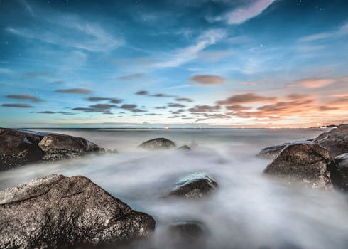 黄昏时分，宁静的海滨雾气弥漫，海浪拍打着岩石