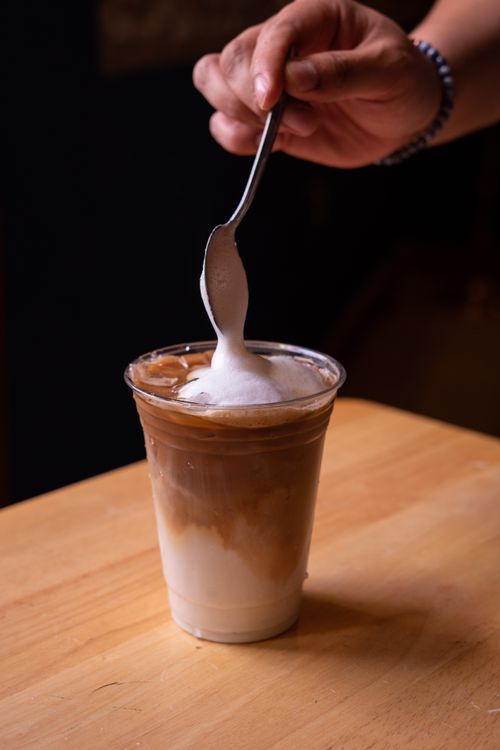 Free A person places foamed milk on iced coffee in San Miguel de Allende. Stock Photo